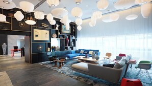 Un salon moderne avec un canapé bleu, une table rouge et des lampes suspendues blanches.
