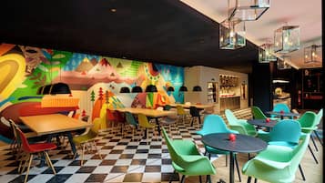 A vibrant restaurant interior with colorful murals, checkered flooring, and a variety of seating options including tables and chairs.
