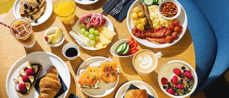 Un bufé de desayuno con diversos platos, como tostadas, huevos, tocino y bollería.