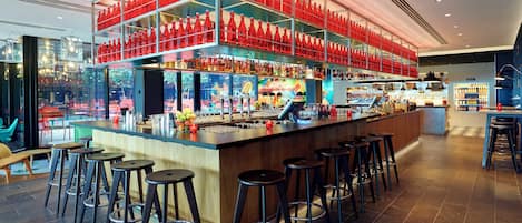 A modern bar with multiple stools, a bar counter, and shelves stocked with bottles.
