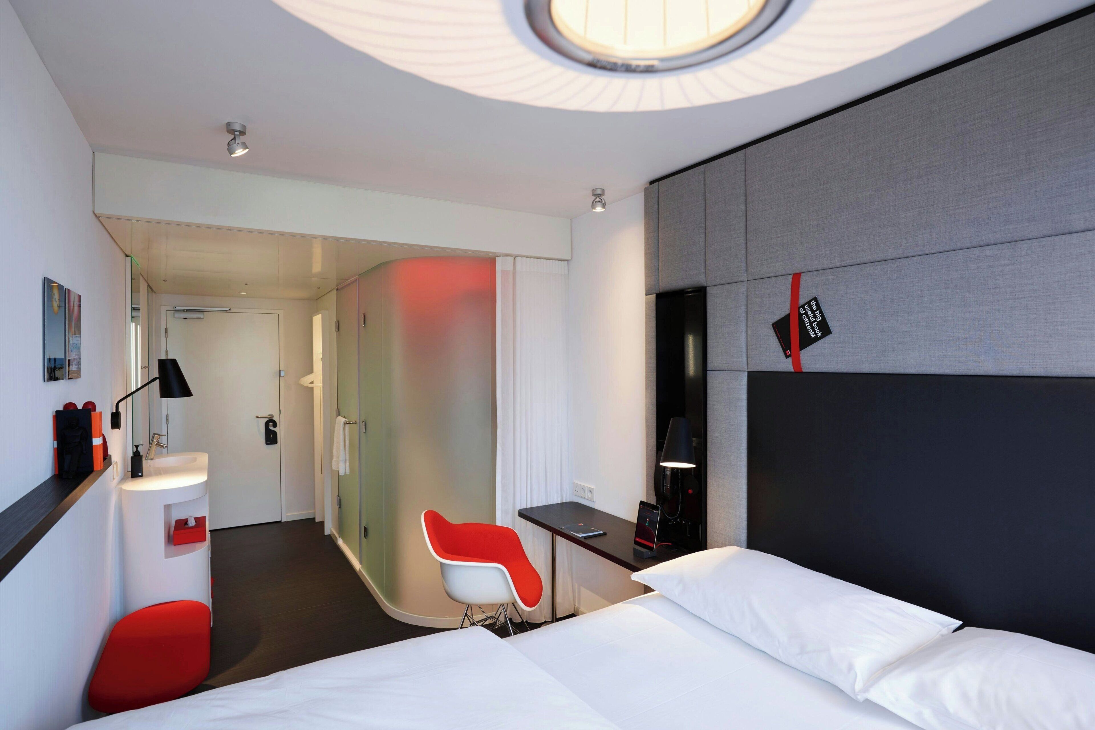 Una camera d'albergo moderna con un letto, una scrivania, una sedia, un tavolino e uno specchio.
