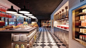 L’intérieur d’un restaurant avec un sol à carreaux, des luminaires suspendus et des étagères remplies de condiments et de boissons.