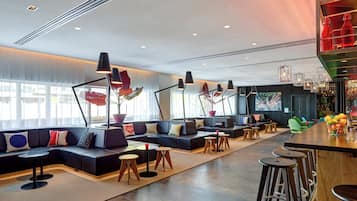 Ein moderner Lounge-Bereich mit Sitzgelegenheiten, Tischen und einer Bar.