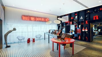 A modern interior with a checkered floor, a red table with a laptop, and a neon sign.