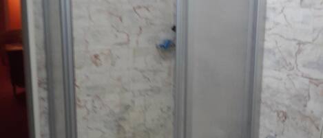 Una cabina doccia in vetro con una parete in marmo.