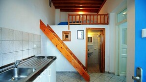 Eine Küche mit einer Holztreppe, einem Spülbecken und Blick ins Badezimmer.
