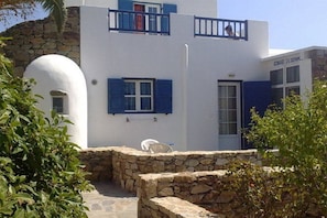 Un bâtiment blanc avec des volets bleus et un mur en pierre.