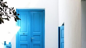 Eine Treppe führt zu einer blauen Tür, ein kleiner Tisch mit einem Stuhl und ein fußbodenbelag mit Muster.
