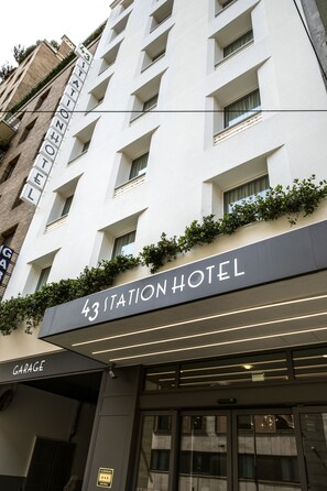 A modern hotel with a sign reading "43 Station Hotel" and a "Garage" entrance.