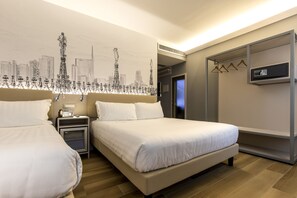 A hotel room with two beds, a cityscape mural, a minibar, and a walk-in closet.