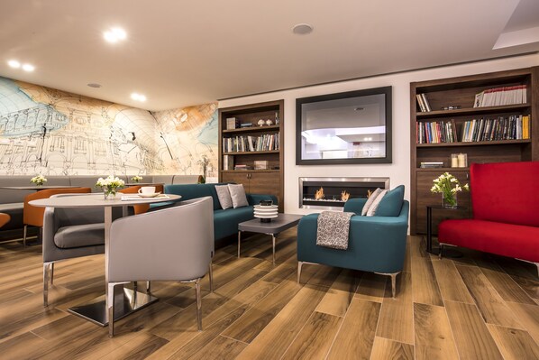 A modern living room with a dining area, a fireplace, and a bookshelf.