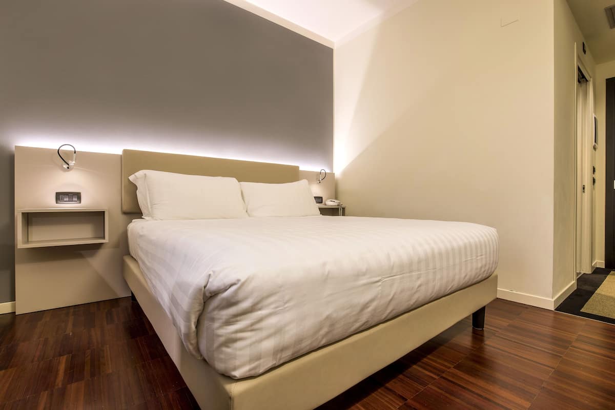 A modern bedroom with a large bed, bedside tables, and a built-in shelf.