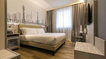 Una camera d'albergo moderna con un letto, una scrivania, una sedia, una televisione e un murale raffigurante un panorama urbano.