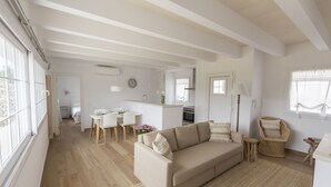 Un espacio habitable amplio con un sofá, una mesa de comedor y una silla de mimbre.
