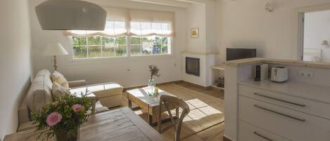 A spacious living area with a wooden dining table, a sofa, a fireplace, and a kitchen area with a microwave and toaster.