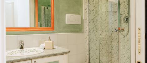 A bathroom with a sink, toilet, and glass-enclosed shower.