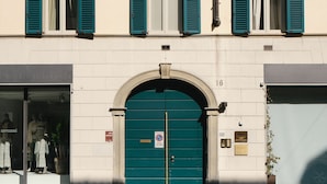 A building with a green door and multiple windows with blue shutters. - Quarenghi16 (Bergamo)