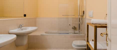 Ein modernes Badezimmer mit einer Badewanne, zwei Waschbecken, einer Toilette und einer Dusche.