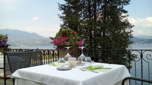 A table set for dining with a view of a lake and mountains in the background. - Hotel La Rondinella (Cannero Riviera)