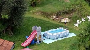 An outdoor swimming pool with a slide, surrounded by grass and trees. - Hotel La Rondinella (Cannero Riviera)