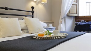 A neatly made bed with white pillows, a tray with breakfast items, and a lamp on the wall. - Prestigia Rooms B&B Firenze (Florence)