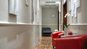 A hallway with a red seating area, a black bench, and a vase with flowers. - Prestigia Rooms B&B Firenze (Florence)