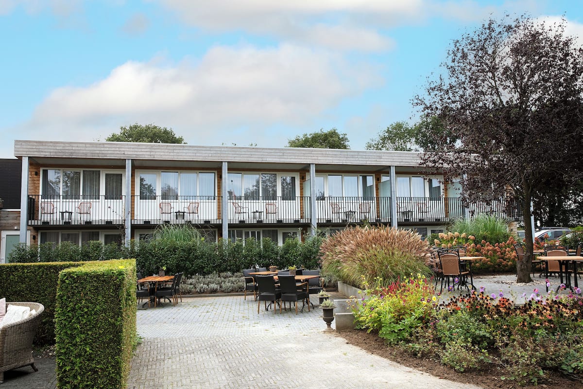 Ein Gebäude mit Balkon, Sitzgelegenheiten im Freien und einem Garten.