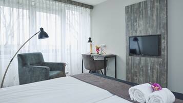 Een hotelkamer met een bed, een bureau, een stoel, een televisie en een lamp.
