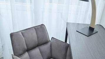 A modern chair with a cushioned seat and backrest, positioned next to a wooden table with a black lamp.