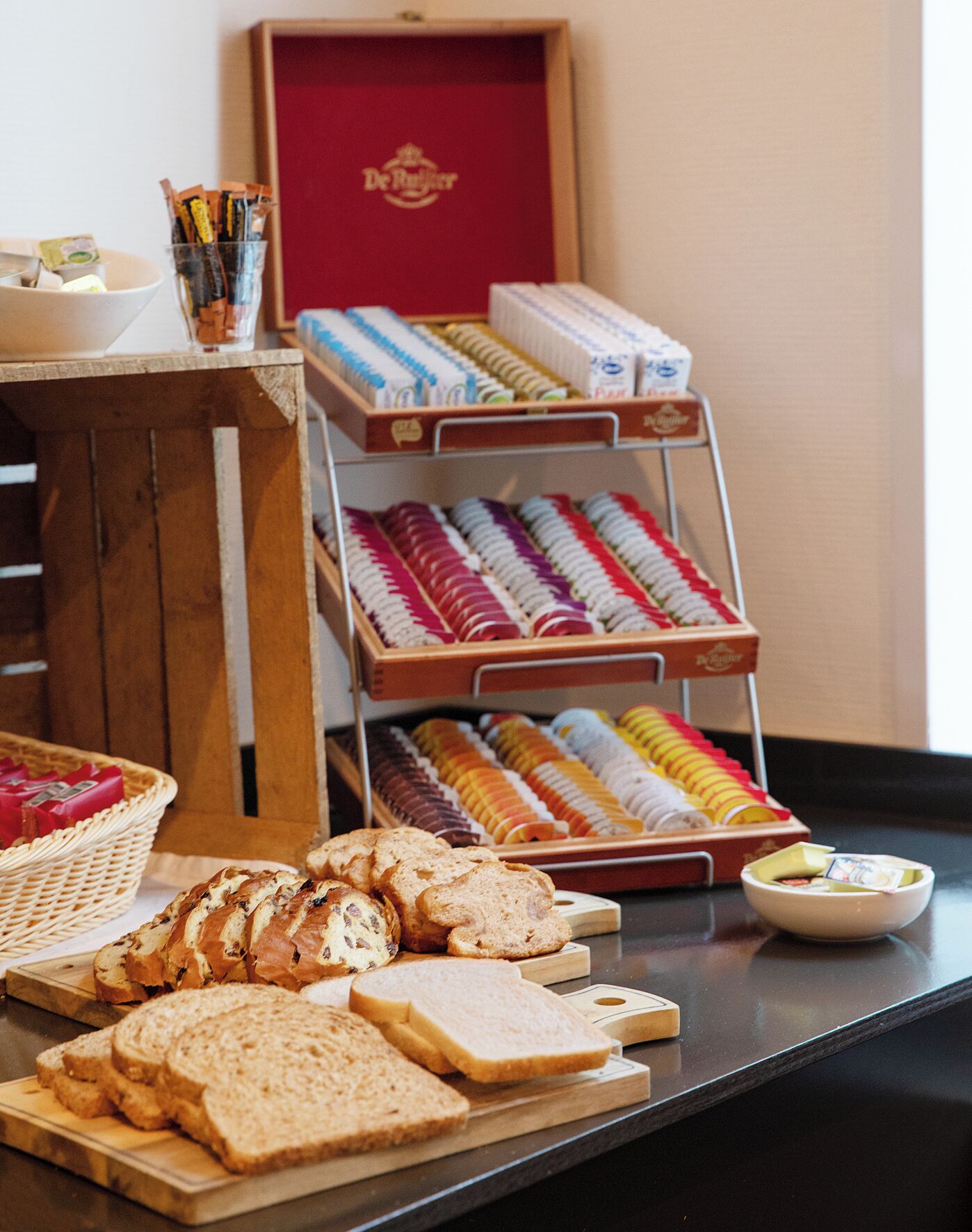 A breakfast buffet with various breads, pastries, and packaged goods.