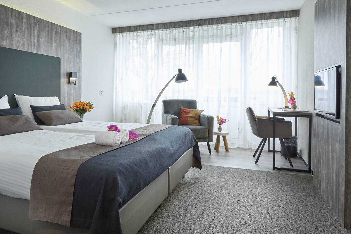 Ein Hotelzimmer mit Bett, Schreibtisch, Stuhl und Fernseher.