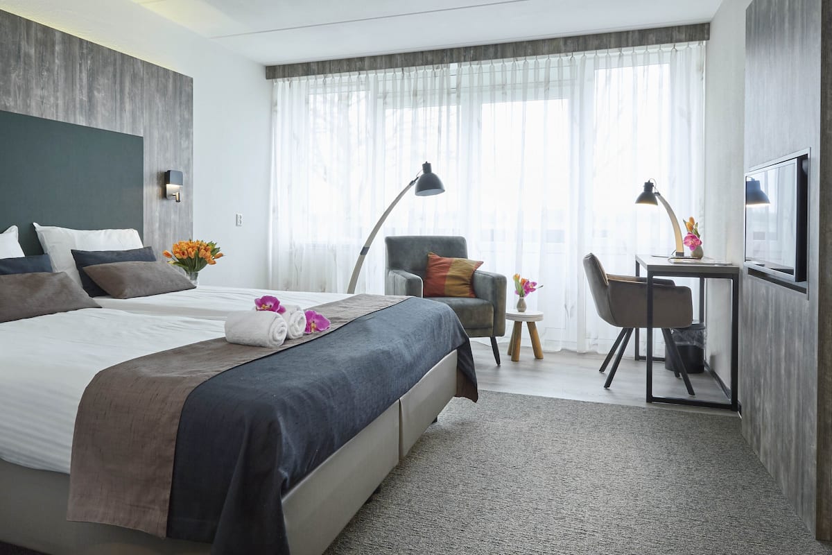 Ein Hotelzimmer mit Bett, Schreibtisch, Stuhl und Fernseher.
