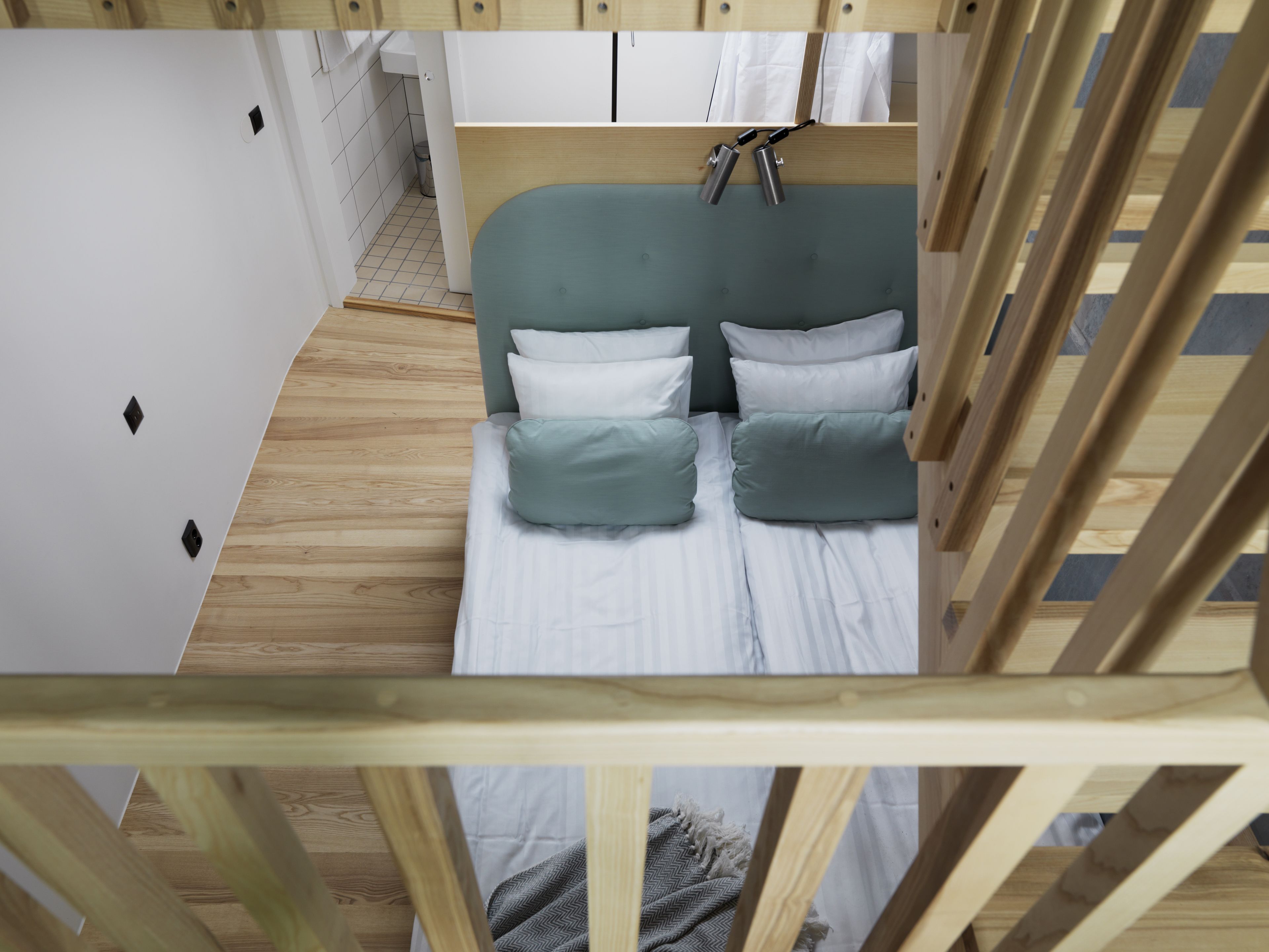 Una habitación compacta y moderna con una cama litera, un kitchenette pequeño y piso de madera.