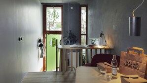 A modern kitchen with a wooden table, a laptop, and a bicycle. - Ohboy Hotell (Malmö)