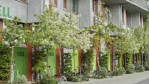 A building with numbered doors, bicycles parked outside, and greenery in front. - Ohboy Hotell (Malmö)