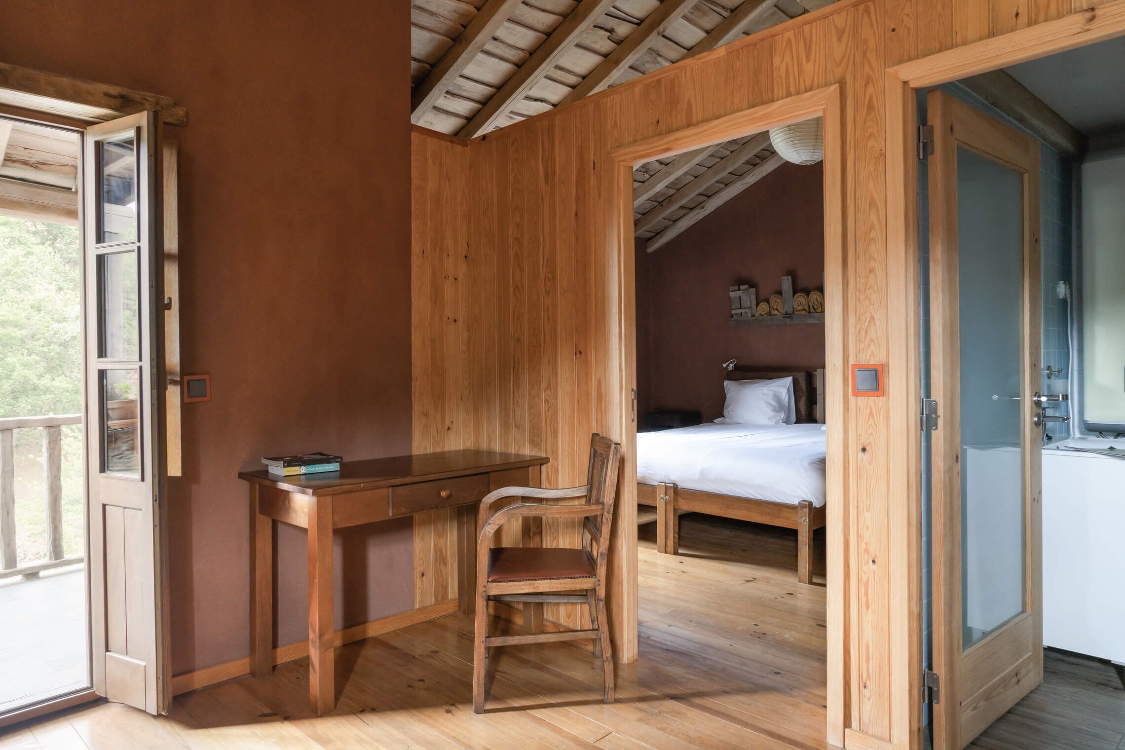 A wooden room with a bed, a desk, and a chair.