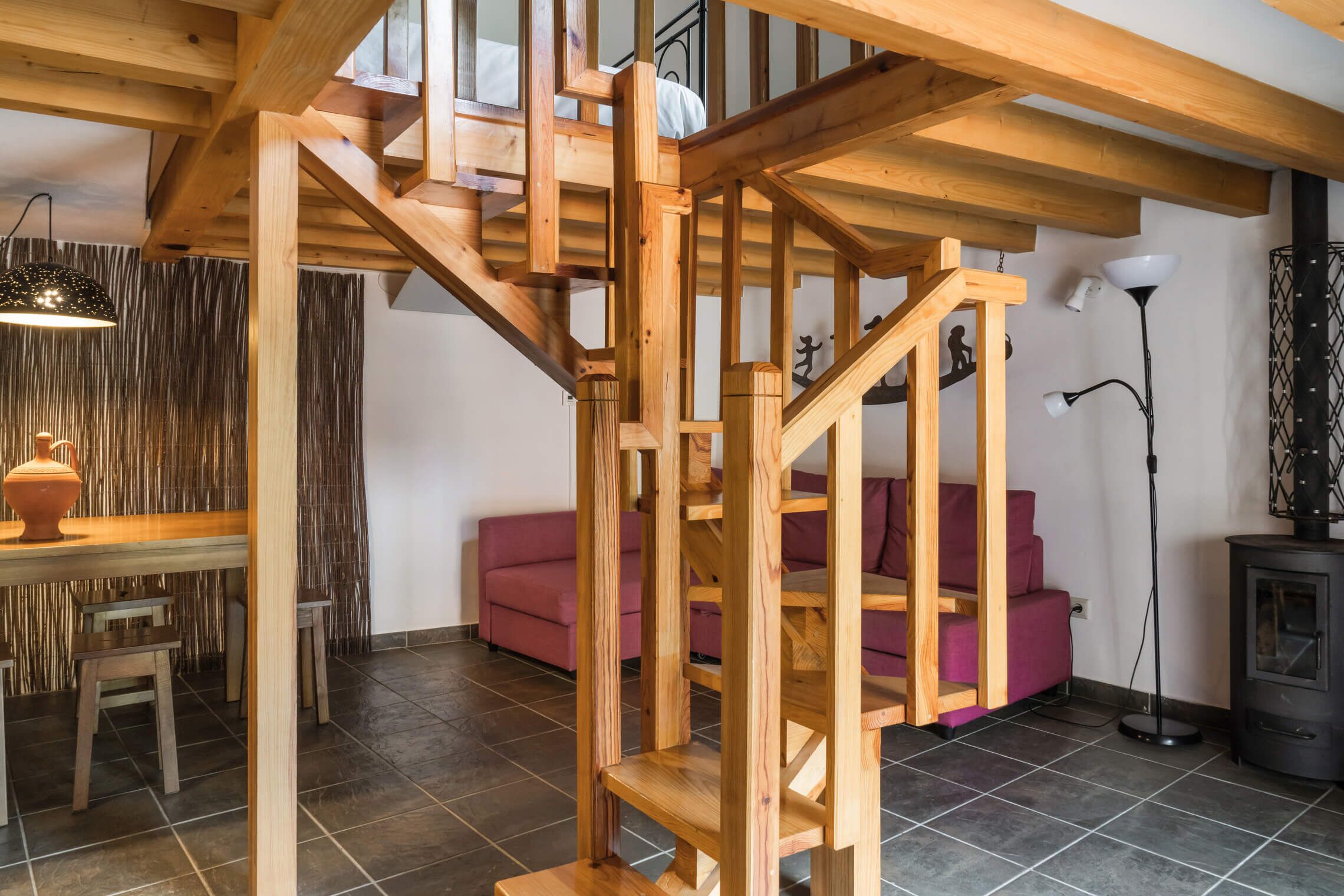 Un escalier en bois dans un salon, avec un canapé et une table.