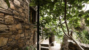 A stone pathway leading to a rustic building with a wooden door and a window. - Cerdeira - Home for Creativity (Lousa)