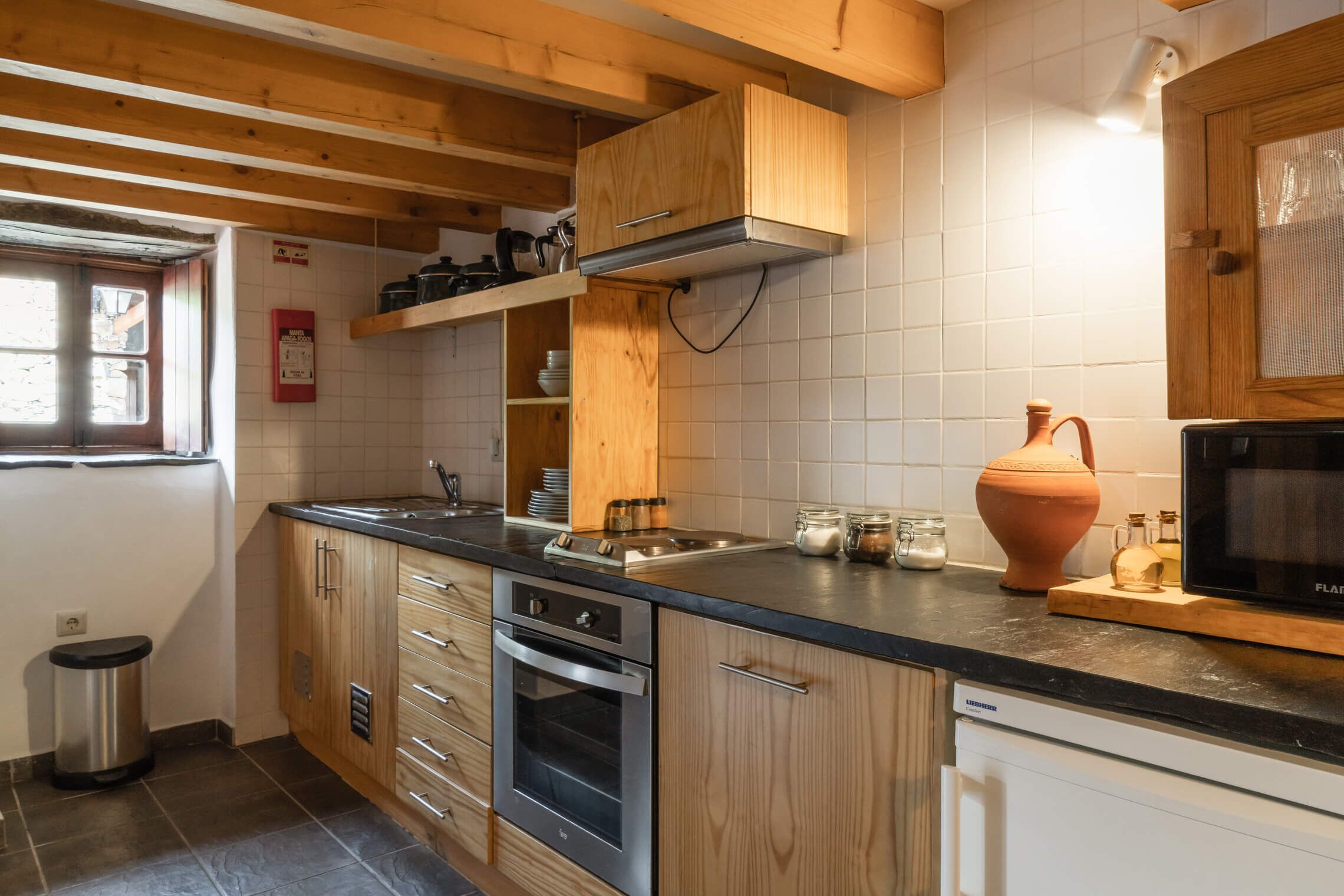 A kitchen with wooden cabinets, a stainless steel oven, a microwave, and a window with a view.