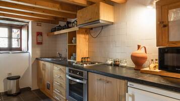 A kitchen with wooden cabinets, a stainless steel oven, a microwave, and a window with a view.