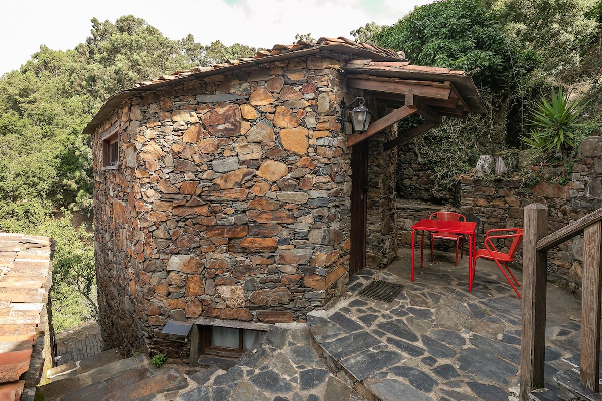 A stone building with a wooden staircase and red chairs.