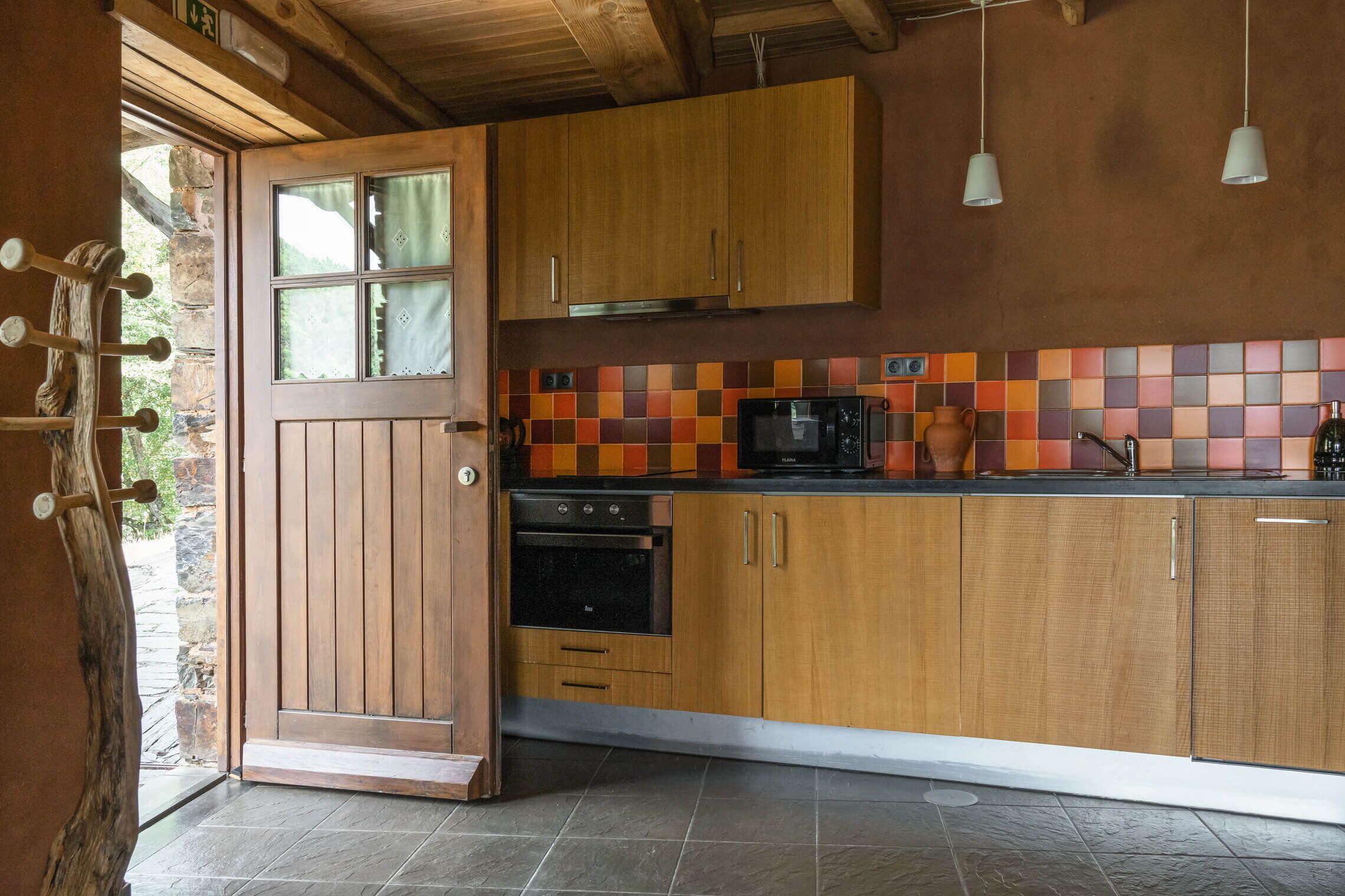 A kitchen with wooden cabinets, a microwave, and a tiled backsplash.