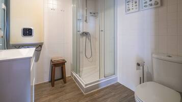 A modern bathroom with a glass-enclosed shower, a toilet, and a sink.