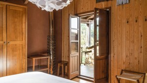 A wooden room with a bed, a bench, a stool, and a bench with a seat. - Cerdeira - Home for Creativity (Lousa)
