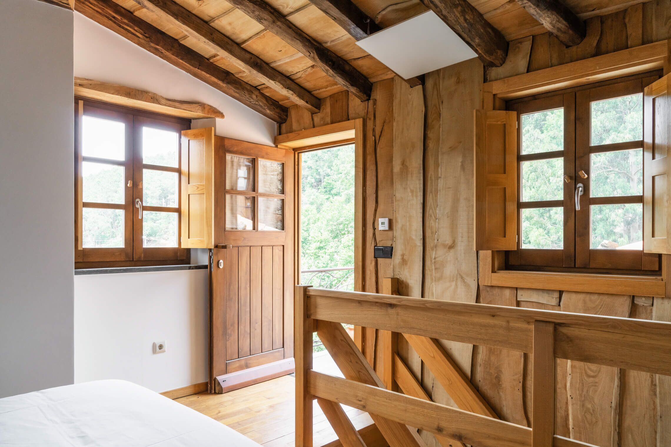 Un interno in legno con un letto, una porta di legno e finestre.