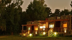 A stone building with a wooden porch and stairs, surrounded by trees. - Posada del Viento (Tandil)