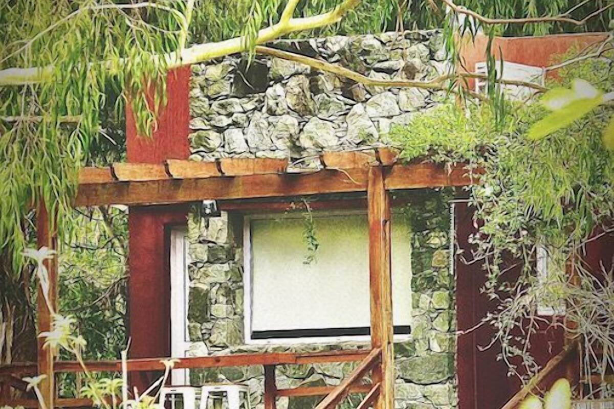 A rustic stone structure with a wooden staircase leading to a window.