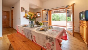 Ein Essbereich mit Tisch für zwei Personen, einer Blumenvase und Blick ins Freie.