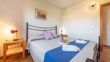 A neatly made bed with a blue bedspread, pillows, a bedside table with a lamp, and a tray of breakfast items.