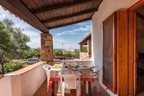 An outdoor dining area with a table set for two, stone pillars, and a view of the surrounding landscape.